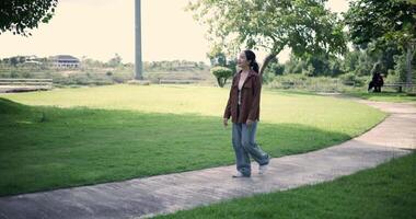Handheld shot, Relaxed woman is enjoying a leisurely stroll and looking around a park filled with fresh air and soft sunlight. Enjoy a happy holiday video