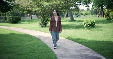 Handheld shot, Relaxed woman is enjoying a leisurely stroll and looking around a park filled with fresh air and soft sunlight. Enjoy a happy holiday video