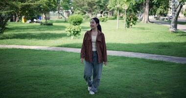 Handheld shot, Relaxed woman is enjoying a leisurely stroll and looking around a park filled with fresh air and soft sunlight. Enjoy a happy holiday video