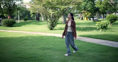 Handheld shot, Relaxed woman is enjoying a leisurely stroll and looking around a park filled with fresh air and soft sunlight. Enjoy a happy holiday video