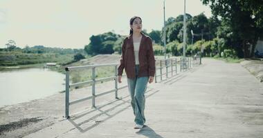 Handheld shot, Relaxed woman is enjoying a leisurely stroll and looking around a park filled with fresh air and soft sunlight. Enjoy a happy holiday video