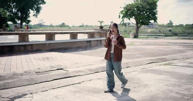 Handheld shot, Happy woman enjoys talking on her mobile phone while walking in a park. A holiday time surrounded by nature video