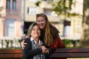Embracing Generations. A Daughter's Love and Support for Her Senior Mother on a Sunny Day in the Park photo