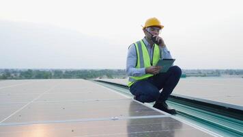 Engineer Wearing Safety Vest and Helmet, Using Tablet to Inspect Solar Panels on Rooftop Installation Site, Conducting Renewable Energy Maintenance, and Ensuring Efficient Solar Power Generation. video
