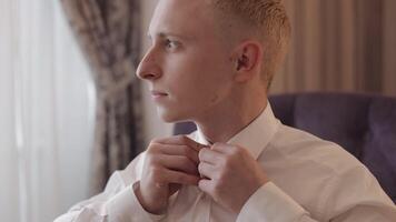 Stylish man in jacket fastens buttons, buttoning white shirt preparing to go out near window video