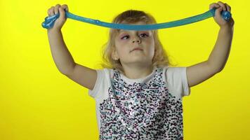 Kid playing with hand made toy slime. Child girl having fun making slime. Yellow background video