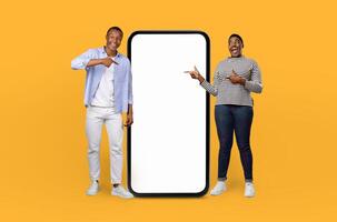 African American lovers standing side by side, pointing at an empty screen in the center of the frame. Both are focused on the screen, their gestures indicating attention photo