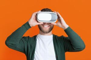 A man in a cardigan is seen holding a virtual reality headset. The man appears to be examining the headset, possibly preparing to use it for a VR experience. photo
