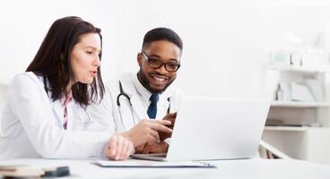 Two practitioners consulting, using laptop and discussing diagnosis questions in meeting room photo