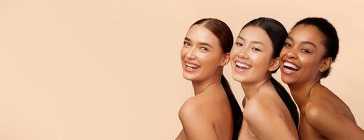 Three Diverse Ladies Models Smiling To Camera Posing Over Beige Background. Studio Shot photo