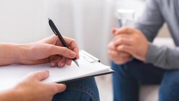 Psychologist taking notes during session with depressed patient, close up, panorama photo