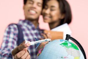 African American couple is holding a model airplane and a globe in their hands, showcasing a shared passion for travel and exploration. The model airplane symbolizes a desire for adventure photo