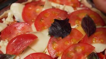 Pizza Tomatoes Mozzarella - Close-up of a pizza being made with sliced tomatoes, mozzarella cheese, and basil leaves. video