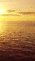 Sea water surface at sunset. Vertical aerial view, camera flies over calm golden sea. Sun glare. Abstract nautical summer ocean nature. Holiday and travel concept. Nobody. Weather and climate change video