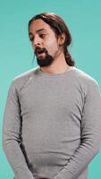 Vertical Portrait of bored man lacking enthusiasm to do anything, yawning, wasting time, isolated over studio background. Lazy person living monotonous life, having sleepy dull facial expression, camera B video