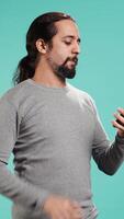 Vertical Joyous man with positive emotion enjoying talking with friends in phone call using smartphone, studio background. Happy person with smile on face, receiving good news during telephone call, camera B video