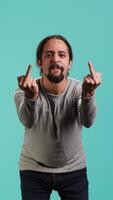 Vertical Irked man fighting with friend, doing middle finger sign gesturing, isolated over studio background. Outraged person arguing during conversation, doing obscene hand gestures, camera A video