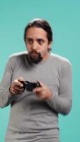 Vertical Upbeat person playing intense gaming console game, having fun, isolated over studio background. Joyous man pleased after being victorious in videogame, defeating all enemies using gamepad, camera B video