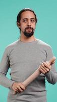Vertical Portrait of menacing man threating to hit enemy during fight. Wrathful Arab person full of rage intimidating mate, holding weapon, isolated over studio background, camera B video