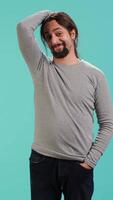 Vertical Portrait of shy man putting hand on head, feeling ashamed, isolated over studio shot. Self conscious person feeling insecure while seeing crush, feeling need to express emotions, camera A video