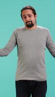 Vertical Man shrugging shoulders, expressing uncertainty or helplessness, having troubled facial expression. Person unable to provide assistance to friend, feeling powerless, studio background, camera A video