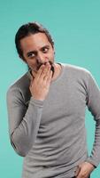 Vertical Frisky playful man blowing kisses to camera, being flirty. Lively charming person having fun sending air kisses, doing romantic gesturing, isolated over studio background, camera B video
