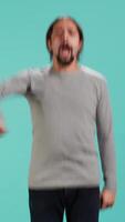 Vertical Man jumping from joy in excitement while cheering for favorite sports team, studio background. Person celebrating after victory, showing intense enthusiasm, supporting team during game, camera A video