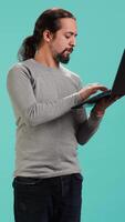 Vertical Man composing email, typing on laptop keyboard, excited to log off after work. Cheerful person sending mail online, brainstorming message idea, isolated over studio background, camera A video