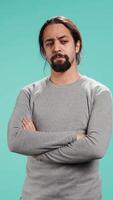 Vertical Grumpy man crossing arms, feeling upset by events, isolated over studio background. Portrait of stressed moody person shaking head, left speechless by troubling news, camera B video
