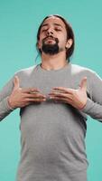 Vertical Portrait of man inhaling and exhaling to relax and gain positive energy, eliminating stress. Person doing breathing exercises for wellbeing, isolated over studio background, camera B video