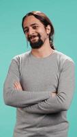 Vertical Portrait of joyous man holding hands together, smiling, looking pleased, isolated over studio background. Upbeat person dressed casually exulting, feeling satisfied, camera B video