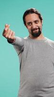 Vertical Happy man asking for money with hand gesture, rubbing fingers together in order to receive cash payment. Jolly person requesting financial bribe, doing extorsion, studio background, camera B video