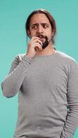 Vertical Portrait of man feeling perplexed by confusing information, isolated over studio background. Person scratching head, looking around with puzzled facial expression, camera B video
