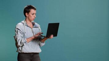 Casual woman browsing web on her laptop for freelance work in studio, remote network. Wireless computer user blogging on a new interface, trendy modern tech person. Camera B. video