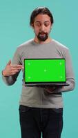 Vertical Portrait of worker holding isolated screen laptop, doing important work for company, studio background. Employee with chroma key device at work solving job tasks, camera A video