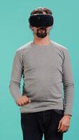 Vertical Tech enthusiast wearing virtual reality goggles, doing zooming in gestures. Arab man using high tech futuristic modern VR glasses, making tactile touching gesturing, studio background, camera A video