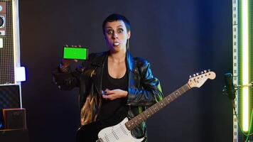 Cool rebellious rock star does a live performance pointing to copy space screen at nightclub, feeling powerful in her leather jacket and dark make up. Trendy powerful girl performing. Camera A. video