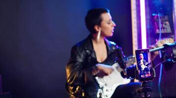 Voice training instructor teaching people to play the guitar on online lesson live tutorial, doing a practice session during virtual class. Superstar vocal coach does singing lessons. Camera A. video