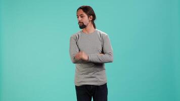 Portrait of man scratching neck with fingers, listening for unfamiliar sound, concentrating on finding source. Person tilting head, focusing on identifying noise, studio background, camera A video