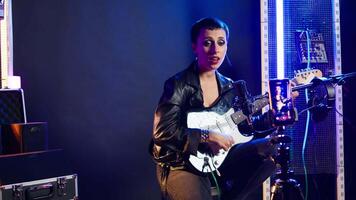 Musical instructor influencer creating content while playing guitar and singing alternative music, live audience online concert. Artist broadcasting her performance on streaming session. Camera A. video