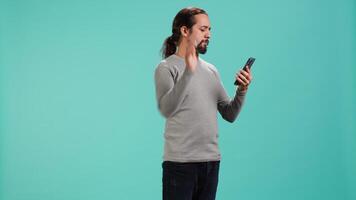 Portrait of smiling man talking with friends in phone call using smartphone, studio background. Jolly person feeling positive after receiving good news during telephone call, camera A video