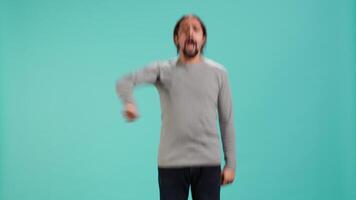 man Hoppar från glädje i spänning medan glädjande för favorit sporter team, studio bakgrund. person fira efter seger, som visar intensiv entusiasm, stödjande team under spel, kamera en video