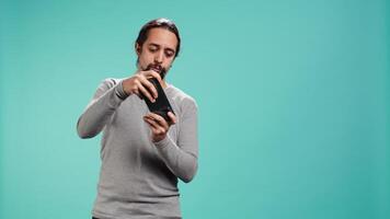 Man playing intense singleplayer videogames on smartphone, enjoying hobby. Gamer enjoying entertaining interactive game on phone, having fun, isolated over studio background, camera B video