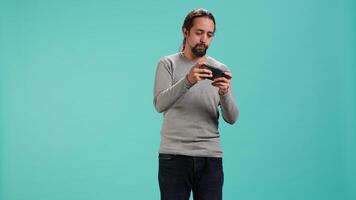 Man playing intense singleplayer videogames on smartphone, enjoying hobby. Gamer enjoying entertaining interactive game on phone, having fun, isolated over studio background, camera A video