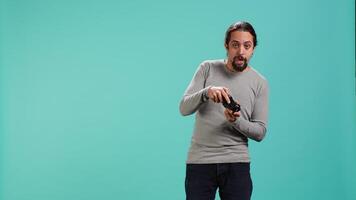 Gamer with disappointed look on face after receiving game over screen, holding controller. Man upset after losing videogame, playing with gamepad, isolated over studio background, camera A video