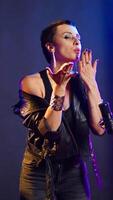 Vertical Fierce bold superstar blowing air kisses and acting playful in musical studio, being flirty with audience at nightclub. Popular iconic artist in leather jacket loving the support from fans. Camera A. video