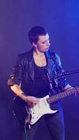 Vertical Punk rock girl with a grunge edgy style performing with a bass guitar in urban studio. Female rock star with bold attitude and fierce stage presence creating an iconic live performance. Camera B. video