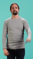 Vertical Upset man showing thumbs down sign gesturing, being disapproving. Disappointed Arab person against gaming, doing rejection hand gesture, isolated over studio background, camera A video