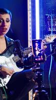 Vertical Musical instructor influencer creating content while playing guitar and singing alternative music, live audience online concert. Artist broadcasting her performance on streaming session. Camera A. video