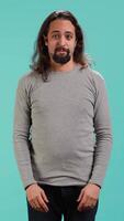 Vertical Portrait of spiteful man making exaggerated silly faces, mimicking someone, doing mocking gesturing. Person making goofy facial expressions, being playful, making fun, studio background, camera A video